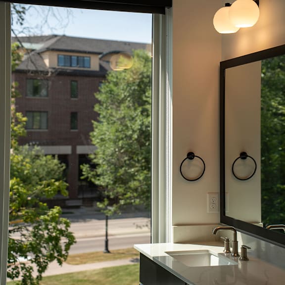 A bathroom with a large mirror and a window overlooking a street.