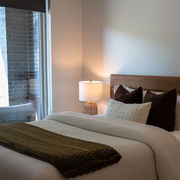 A bed with a white comforter and a green throw blanket.