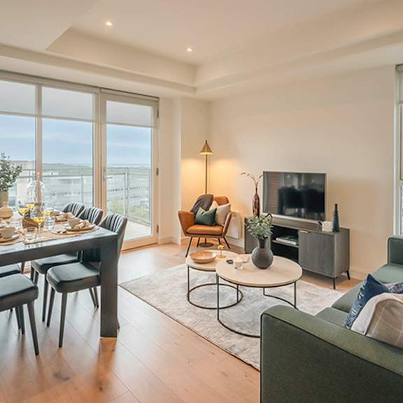 A living room with a grey couch, a coffee table, a dining table, and a television at Cherrywood Apartments, D18 VY3V, DUBLIN 18