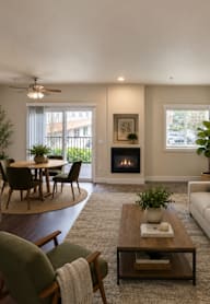 A living room with a fireplace, a couch, a chair, a coffee table, and a dining table.