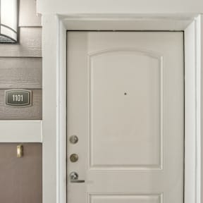 A white door with a number plate on the wall above it.