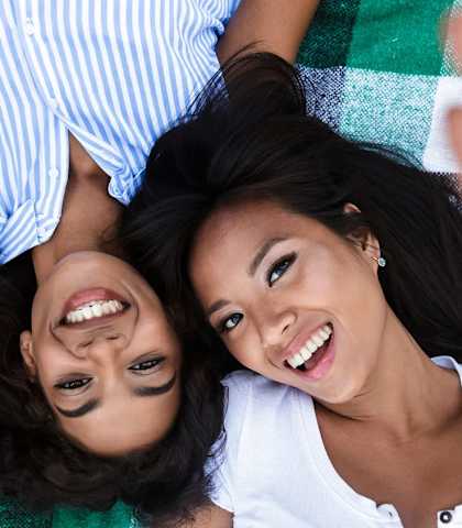 two women laying on a blanket and smiling