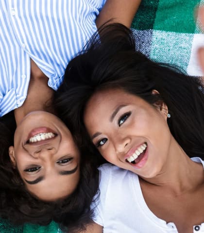 two women laying on a blanket and smiling