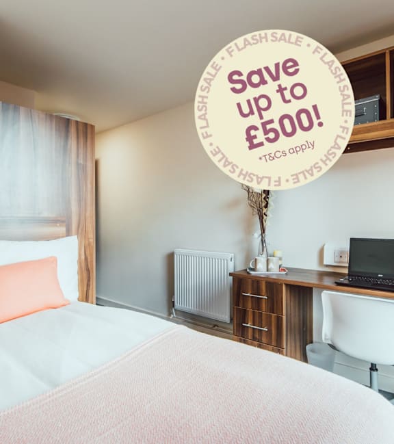 A bedroom with a bed, desk, and a sign offering savings on money.