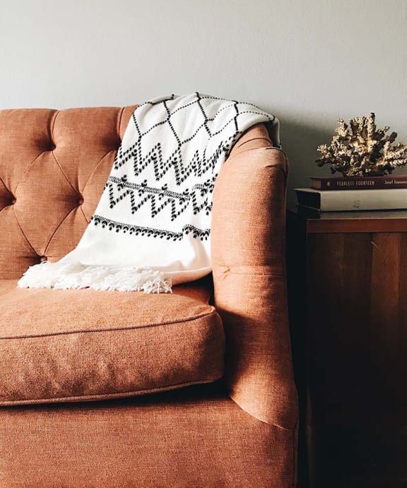 a brown chair with a white and black blanket on it