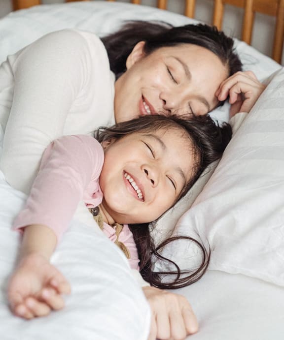a mother and daughter sleeping in bed together