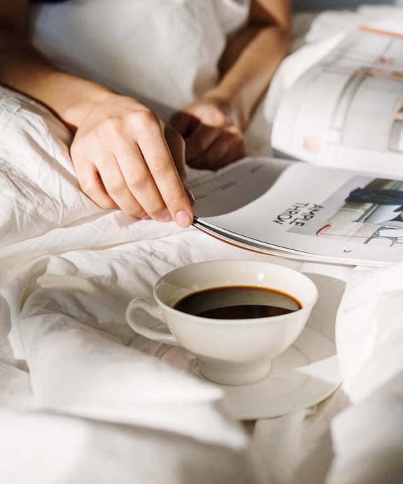 a person in bed with a cup of coffee