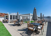 Thumbnail 7 of 42 - A patio with a table and chairs under black and white umbrellas. 605 Place Student Housing & Co-Living, St George, 84770