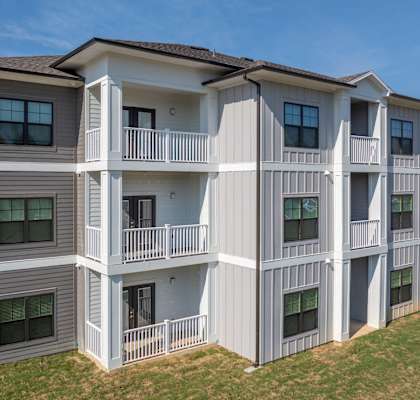 A large two-story apartment building with balconies and multiple windows.