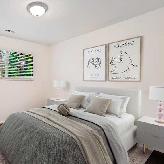 A bedroom with a bed, a chair, and pictures of Matisse and Picasso on the wall.