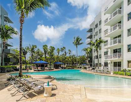 A swimming pool surrounded by palm trees and lounge chairs.