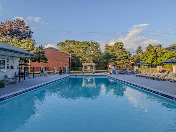 A large swimming pool in a backyard surrounded by trees and a house.