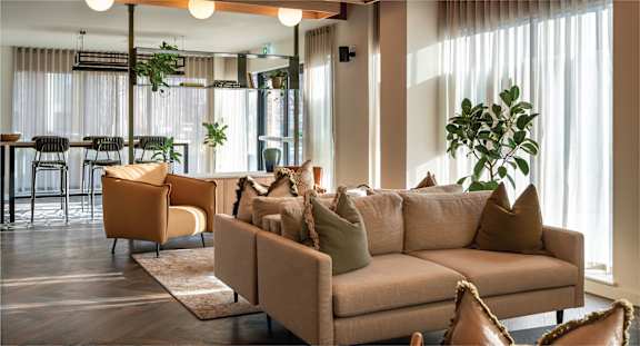 A living room with a large beige sofa and a dining table with chairs.