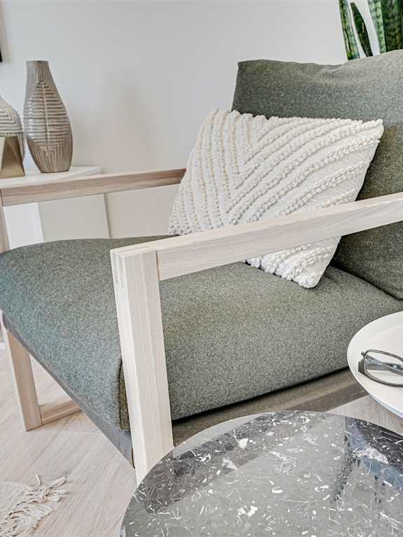 A grey couch with pillows and a blanket is on a patio.