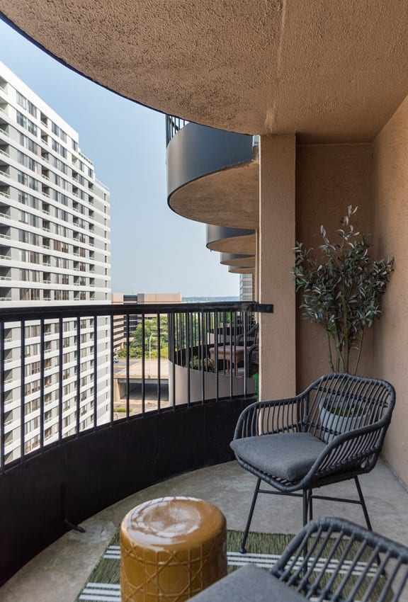 a balcony with two chairs and a table and a building in the background