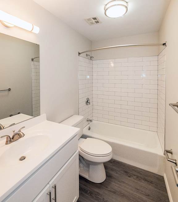 A white bathroom with a toilet, sink, and shower at Kings Gate West Apartments, Camillus, NY, 13031