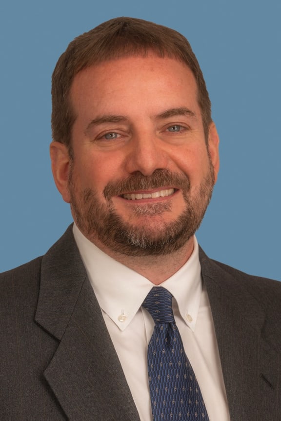 a man wearing a suit and tie and smiling