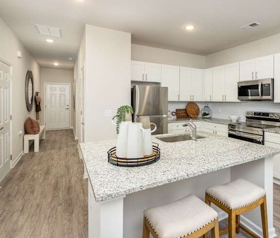 a white kitchen with a marble counter top and white cabinets