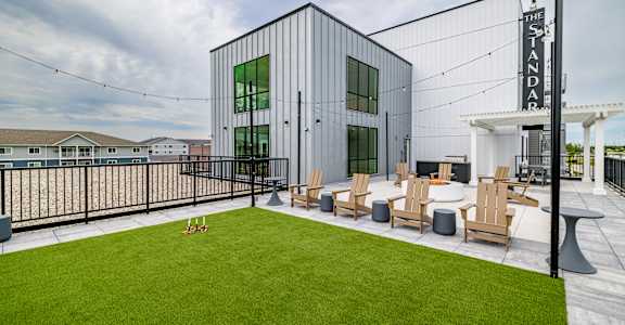 a patio with lawn chairs and a building with a sign on it at The Standard on 32nd, West Fargo, North Dakota