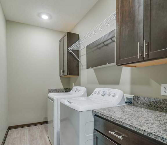 a white washer and dryer in a kitchen with wooden cabinets