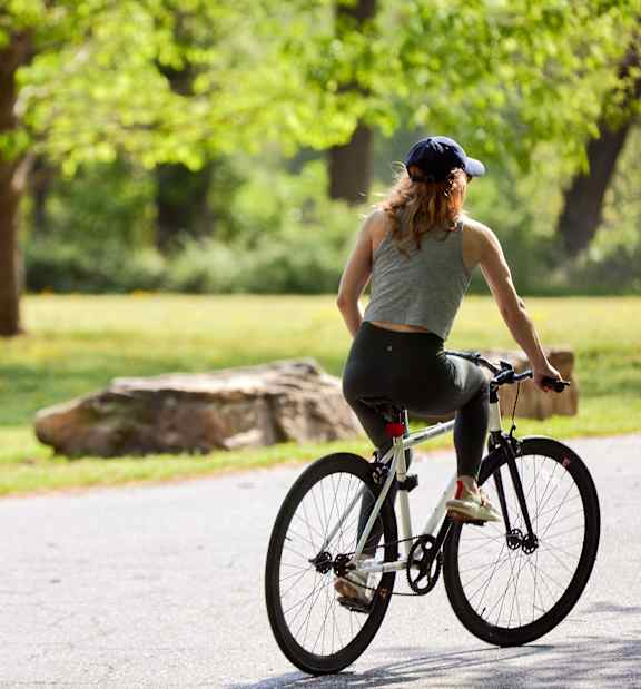 A woman riding a bike on a paved path in a park.