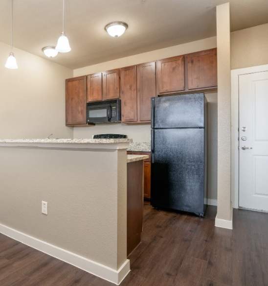 A kitchen area with a black refrigerator and a microwave above the counter.