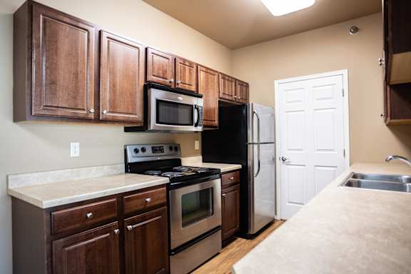 A kitchen with brown cabinets and black appliances.