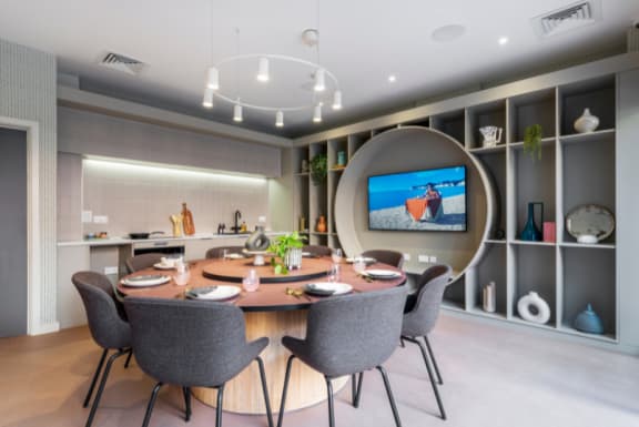 a dining room with a table and chairs and a tv on the wall