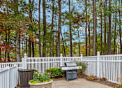 Thumbnail 26 of 32 - A backyard with a white fence and a grill.