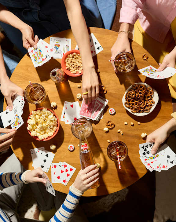 A group of people sitting around a table playing card games.