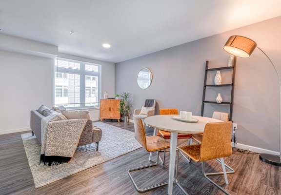 A modern living room with a grey sofa, a white table, and orange chairs.