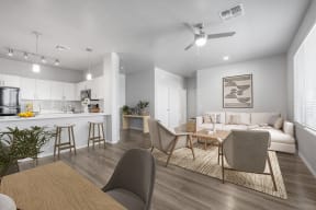 a living and dining room with a kitchen in the background and a ceiling fan overhead