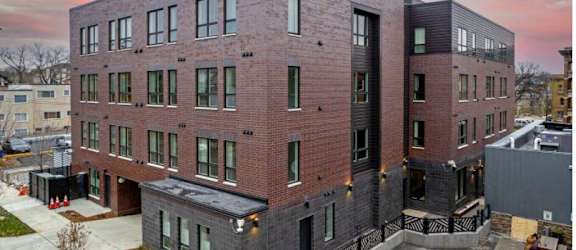 a brick apartment building with a sunset in the background