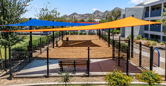 A playground with a blue and orange canopy.