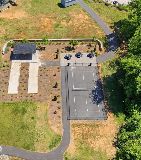 A bird's eye view of a residential area with a house, a swimming pool, and a parking lot.
