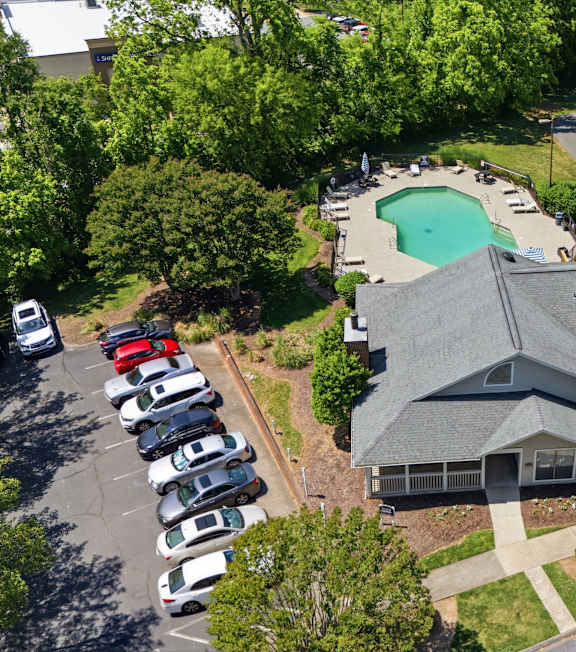 A bird's eye view of a residential area with a house, a swimming pool, and a parking lot.