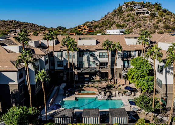 A large house with a pool surrounded by palm trees.
