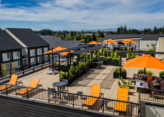 a rooftop patio with orange umbrellas and tables and buildings