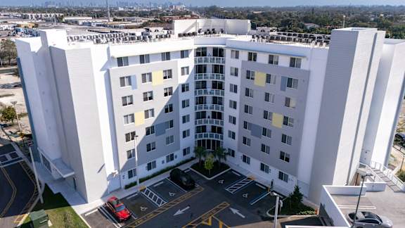 A large white building with a parking lot in front.