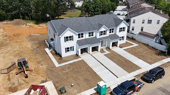 A house under construction with a truck and a car parked in front.