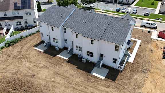 A white house with a grey roof is surrounded by a dirt area.