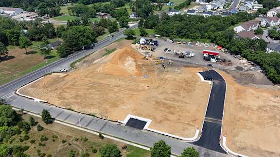 An aerial view of a construction site with a large open area and a road curving around it.