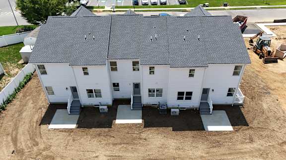 A white house with a grey roof is being built.