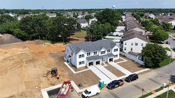 A house under construction with a red truck and a white van parked in front.