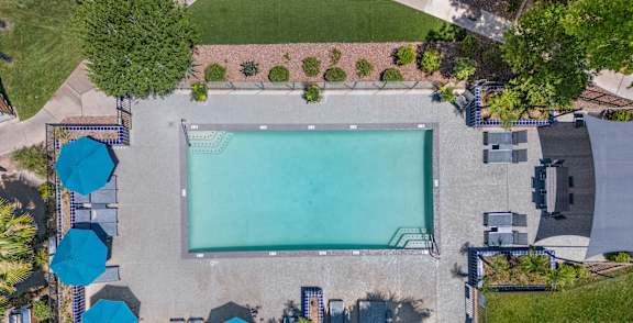 A basketball court is surrounded by a pool and lounge chairs.