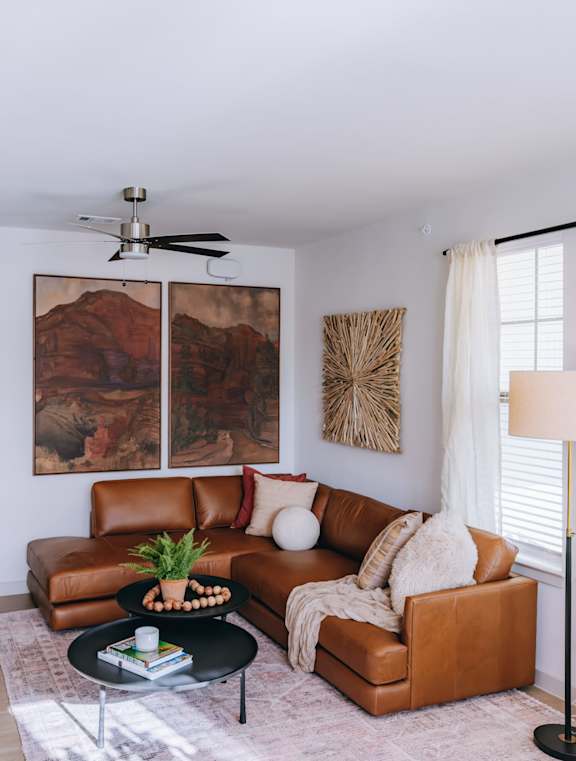 A living room with a brown leather couch and a painting on the wall. at Northwoods, Texas, 77388