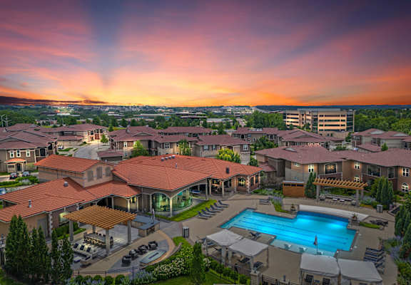 an aerial view of a resort with a swimming pool at sunset