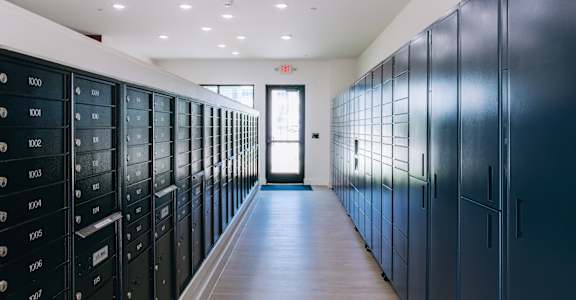 A long hallway with a series of lockers on the left and a door at the end. at Northwoods, Texas, 77388
