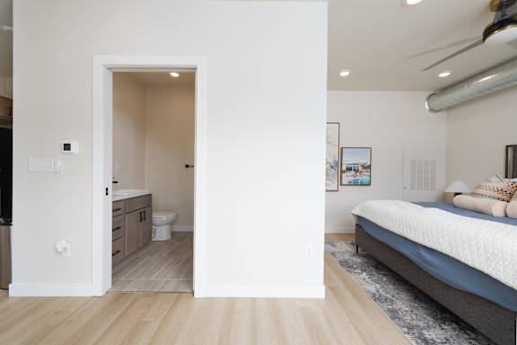 A bedroom with a bed, a dresser, and a bathroom visible through an open door.