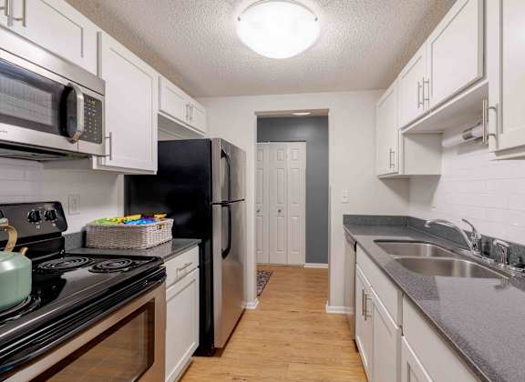 A kitchen with black and white appliances and wooden floors.